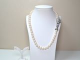 un mannequin blanc portant un collier de perles et une broche en forme de fleur