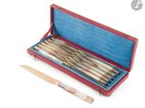 un étui rouge contenant un lot de six stylos et un couteau