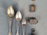 plusieurs cuillères en argent et un repose-cuillère posés sur une table à côté d'un rocher