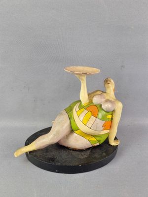 figurine représentant une femme allongée sur le ventre, un frisbee à la main