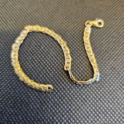 gros plan d'un bracelet en or sur une surface noire