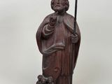 a wooden statue of a man holding a staff and a bird