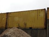 a pile of dirt in front of a yellow container