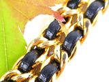 a close up of a gold chain bracelet with black beads