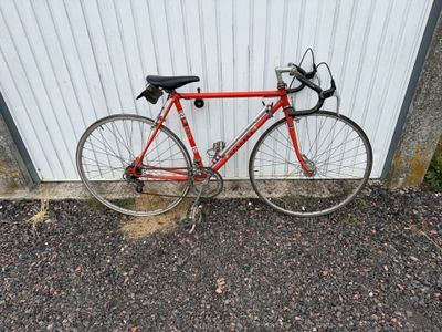 un vélo rouge appuyé contre un mur blanc