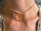 un gros plan sur une femme portant un collier orné d'une fleur