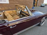 a maroon convertible car parked in front of a brick building