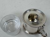 a glass of water next to a silver teapot