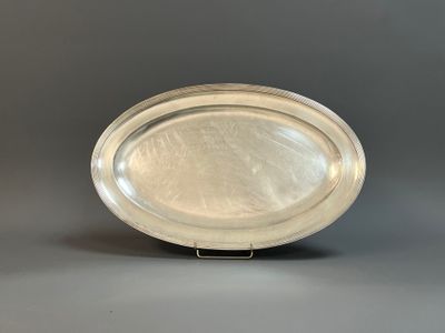 an oval silver plate on a stand on a gray background