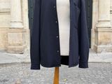 un mannequin devant un immeuble, vêtu d'un manteau