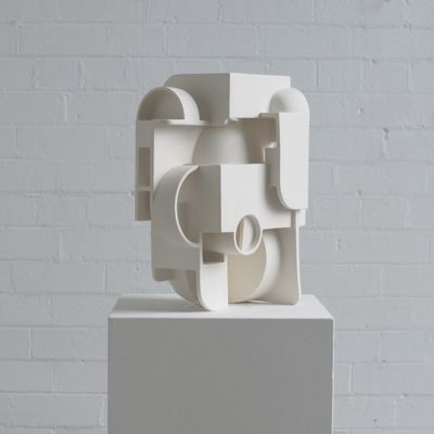 une sculpture blanche posée sur un socle devant un mur de briques