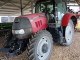 un tracteur rouge garé sur la terre battue