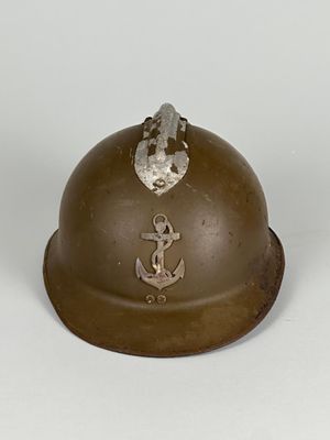 un vieux casque orné d'une ancre sur le côté, posé sur une surface blanche