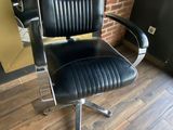 a black office chair sitting in front of a brick wall