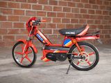 an image of a small motor bike parked in front of a brick wall