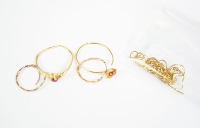 three pairs of gold rings with garnets on them on a white surface