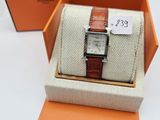 an orange box with a watch inside of it on a white surface
