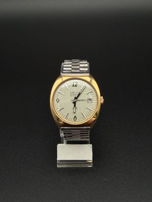 une montre argentée et dorée posée sur une surface noire