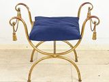 un banc doré sur lequel est posé un coussin bleu
