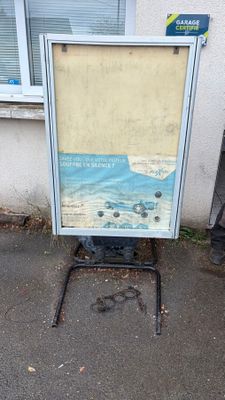 une photo d'un panneau posé sur un support devant un bâtiment