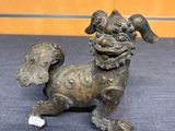 bronze statue of a dog on a blue carpet with a tag in its mouth