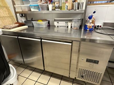 un plan de travail en acier inoxydable dans une cuisine équipée d'une poubelle