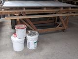 two buckets of paint sitting on a table in a garage