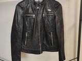 une veste en cuir noir accrochée à un porte-vêtements dans une pièce