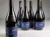 six bottles of wine are lined up on a white surface