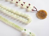 a white bead necklace with green beads on a white table