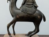 a statue of a man riding a camel on top of a wooden block