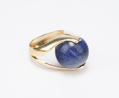 gros plan d'une bague en or avec une pierre bleue