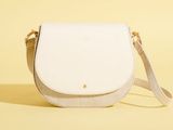 un sac à bandoulière blanc posé sur une surface jaune
