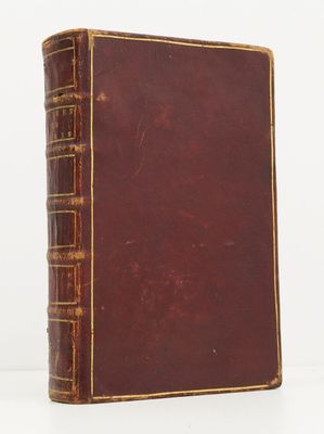 un vieux livre à la couverture marron posé sur une table blanche