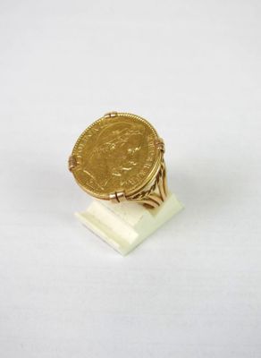 un gros plan d'une bague en forme de pièce d'or posée sur une surface blanche