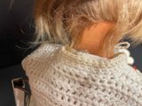 a doll that is wearing a white sweater and holding a cell phone
