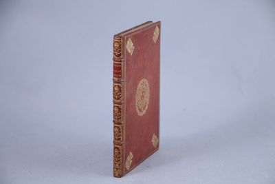 un petit livre rouge orné d'un motif doré