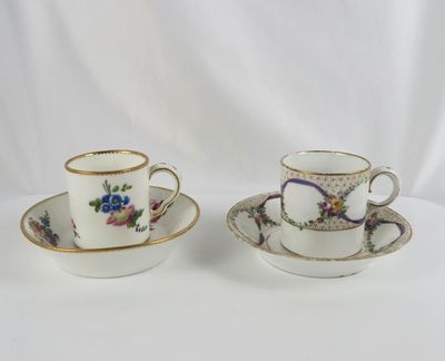 two cups and saucers with floral designs on them on a white surface