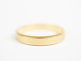 gros plan d'une bague en or sur une surface blanche