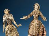 two figurines of a woman and a man dressed in period clothing