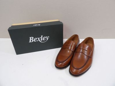 La boîte se trouve à côté d'une paire de chaussures marron sur la table.