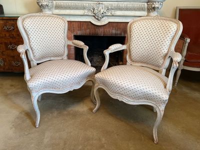 pair of antique french style chairs in front of a fireplace