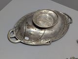 a silver plate with a bowl on top of it on a table