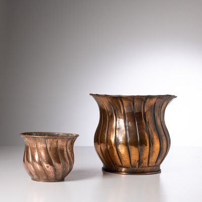 une paire de vases en bronze posés sur une table blanche, sur fond blanc