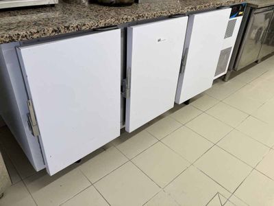 un réfrigérateur blanc posé dans une cuisine, à côté d'un plan de travail