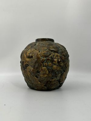 un petit vase posé sur une surface blanche