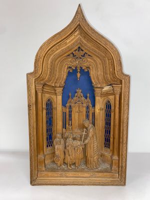 une vieille sculpture en bois représentant un groupe de personnes devant un fond bleu