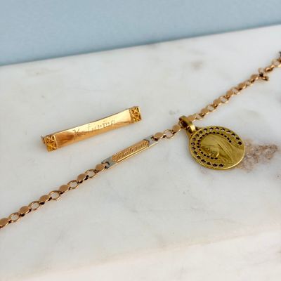 un gros plan d'un collier en or orné d'une pièce de monnaie, posé sur une surface en marbre