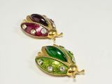 two gold, green, and red enamel ladybug brooches