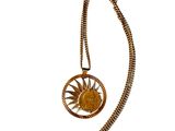 un gros plan sur un collier en or orné d'un soleil